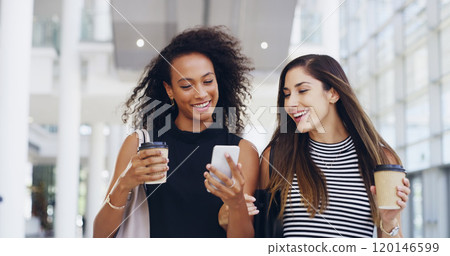 Thats awesome. Cropped shot of two young businesswomen chatting and using a smartphone while walking in an office on a coffee break. 120146599