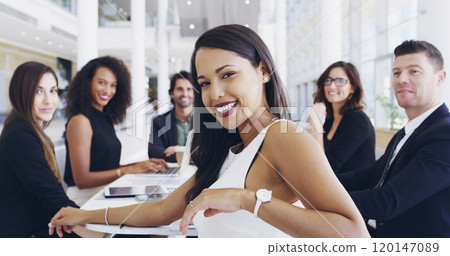 These meetings serve as a platform for success. Cropped shot of a young businesswoman smiling in an office during a meeting with her colleagues in the background. 120147089