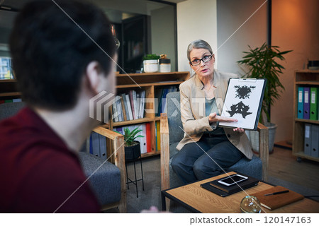 So much more than just an ink splatter. Shot of a mature psychologist conducting an inkblot test with her patient during a therapeutic session. So much more than just an ink splatter. Shot of a mature psychologist conducting an inkblot test with her patient during a therapeutic session. 120147163