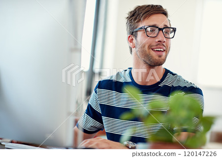 Its always a good day in this office. Shot of a casually-dressed young man at work on a computer. 120147226
