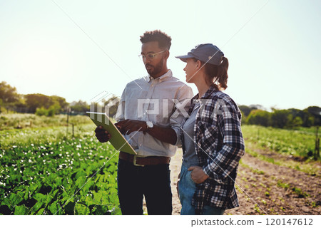 Our growth is phenomenal. Cropped shot of two young farmers looking at a tablet while working on their farm. 120147612