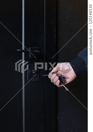Man with key opening front door, closeup 120148530