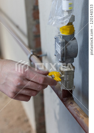 Male hand turns off yellow gas tap. Closeup. Male hand turns off yellow gas tap. Closeup. 120148533