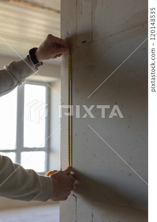 Man planing renovation work in a house. Man with measuring tape. Man planing renovation work in a house. Man with measuring tape. 120148535
