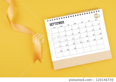 September 2025 desk calendar with yellow ribbon on yellow background. 120148739