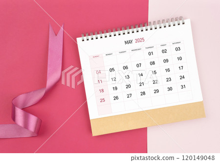 May 2025 desk calendar and pink ribbon on pink background. May 2025 desk calendar and pink ribbon on pink background. 120149048