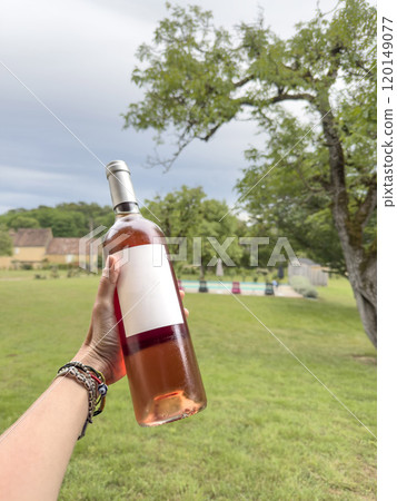 hand holding bottle of pink wine with empty label 120149077