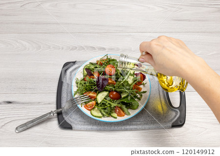 Vegetable salad of tomatoes, cucumbers, greens on the plate with olive oil. Vegetable salad of tomatoes, cucumbers, greens on the plate with olive oil. 120149912