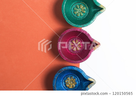 Colorful Diwali Diyas on a vibrant orange and white background for the festival of lights 120150565