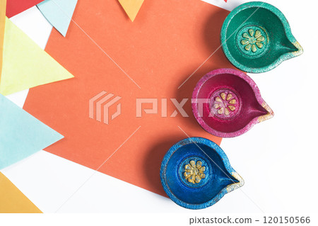Three colorful decorative Diyas on vibrant orange paper with decorative flag for Diwali celebration 120150566