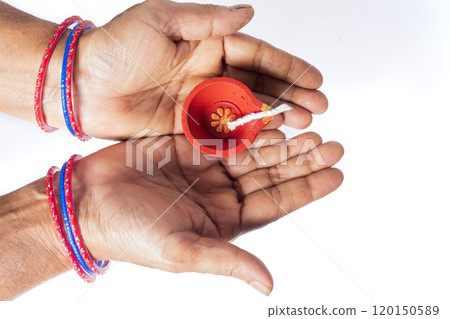 Top view of Indian woman's hands holding Diwali Diya on white background Top view of Indian woman's hands holding Diwali Diya on white background 120150589