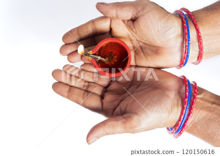 Traditional indian woman hands with colorful bangles holding lit Diwali oil lamp for festival of lights 120150616