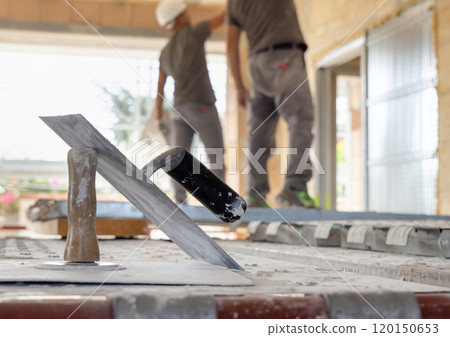 Craftsmen in grey clothes working inside a room standing on scaffoldings during construction Craftsmen in grey clothes working inside a room standing on scaffoldings during construction 120150653