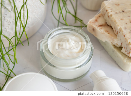 Opened cream jar with white blank lid on marble near green plant close up, cosmetic mockup Opened cream jar with white blank lid on marble near green plant close up, cosmetic mockup 120150658