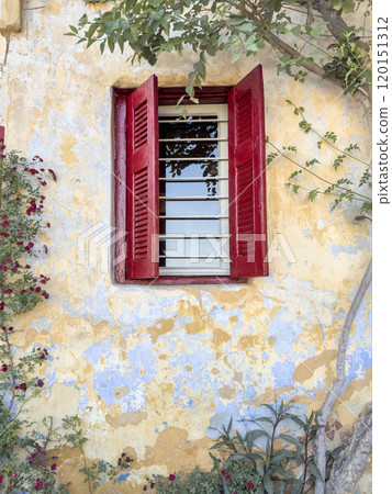 window with red blinds on old wall with flowers 120151312