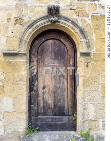 closed old wooden door in a stone wall 120151327