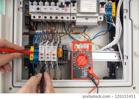Technician Testing Electrical Circuit Board with Multimeter 120151451