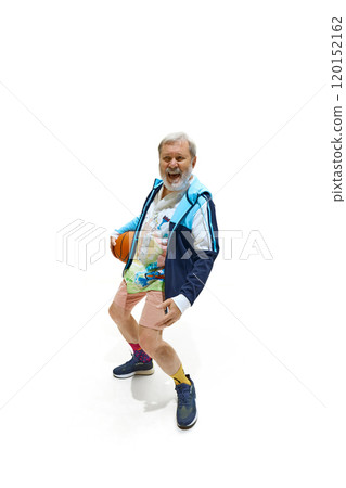 Happy elderly man in mid-sit holding basketball and laughing of joy of game in which he won against white studio background. 120152162