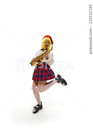 Woman with yellow wig and red beret, playing saxophone in dynamic pose, wearing plaid skirt against white studio background. 120152185