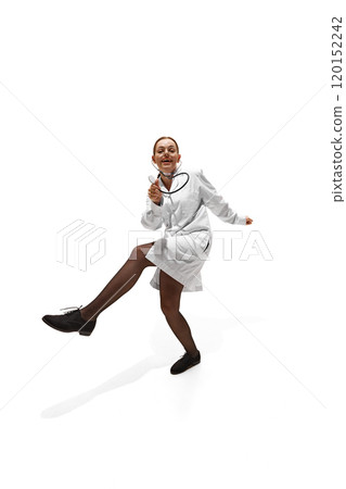 Young woman, dressed as doc, dancing rising hands and legs, showing willingness to help people against white studio background. 120152242