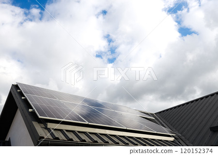 Clean alternative energy. Modern house with solar panels stand-alone photovoltaic plant system on household metal sheet rooftop. Clouds, blue sky background. Professional installation, go green 120152374