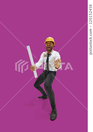 Happy excited man, builder, dressed official attire and engineering helmet, clenching fists against purple background, as he achieved success Happy excited man, builder, dressed official attire and engineering helmet, clenching fists against purple background, as he achieved success 120152456