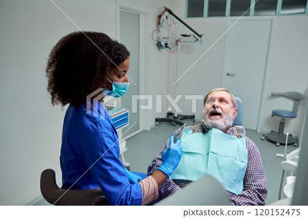 Dentist explains anesthesia effects, helping mature man, patient feel calm and ready for procedure. 120152475