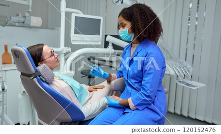 Dentist explains anesthesia effects, helping mature man, patient feel calm and ready for procedure. 120152476