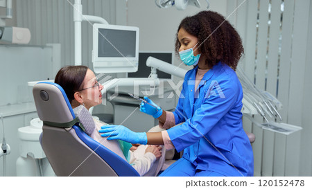 Dentist calmly explains injection process, making sure mature woman, patient feels prepared and relaxed. Dentist calmly explains injection process, making sure mature woman, patient feels prepared and relaxed. 120152478