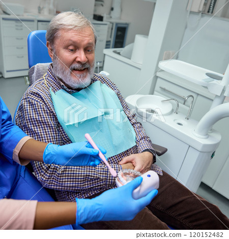Dentist explains benefits of dental veneers, detailing how it can improve patient's smile and dental confidence. Dentist explains benefits of dental veneers, detailing how it can improve patient's smile and dental confidence. 120152482
