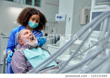 Dentist completes whitening treatment, discussing aftercare tips to help patient maintain bright, healthy smile. 120152484