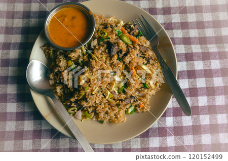 A plate of bhat bhuteko or nepali fried rice with vegetables and buffalo meat, accompanied by a small dish of spicy tomato sauce, authentic local food of Nepal A plate of bhat bhuteko or nepali fried rice with vegetables and buffalo meat, accompanied by a small dish of spicy tomato sauce, authentic local food of Nepal 120152499