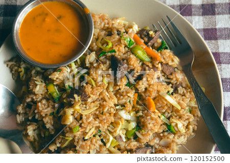 Close up to a plate of nepali buffalo fried rice called bhat bhuteko paired with spicy tomato sauce and served on a checkered tablecloth, authentic local daily staple food of Nepal 120152500