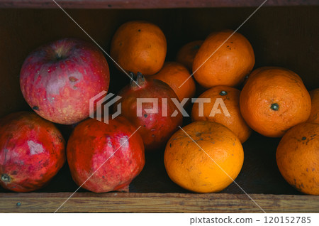 Apples, pomegranates, and oranges on a rustic wooden shop shelf that shows the candid daily life moment and local small business in Pokhara Nepal 120152785