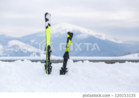 Brightly Colored Skis Resting in Snow With Mountains in the Background Brightly Colored Skis Resting in Snow With Mountains in the Background 120153135
