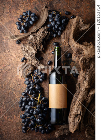 Bottle of red wine with blue grapes and old weathered snags. 120153714