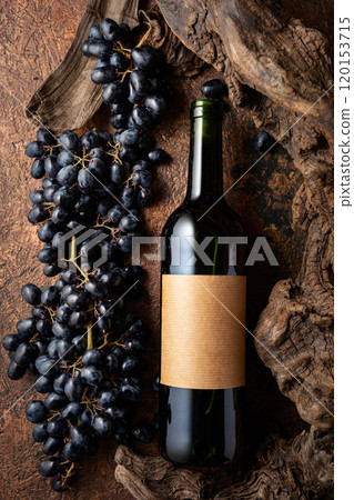 Bottle of red wine with blue grapes and old weathered snags. Bottle of red wine with blue grapes and old weathered snags. 120153715