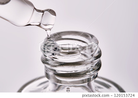 Close-up of a cosmetic bottle with a pipette showing the texture of the serum. Close-up of a cosmetic bottle with a pipette showing the texture of the serum. 120153724