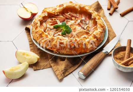 Delicious homemade apple galette with almond flakes and cinnamon on a table 120154030
