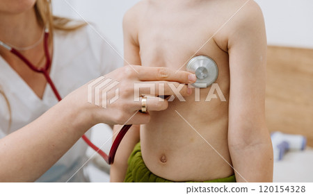 Doctor examines young patient with stethoscope during routine health check-up 120154328