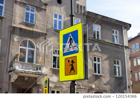 Pedestrian sign in Poland. Warning road sign with a picture of children. Blue and white crosswalk sign. Traffic sign - a pedestrian crossing against the blue sky. Pedestrian sign in Poland. Warning road sign with a picture of children. Blue and white crosswalk sign. Traffic sign - a pedestrian crossing against the blue sky. 120154366