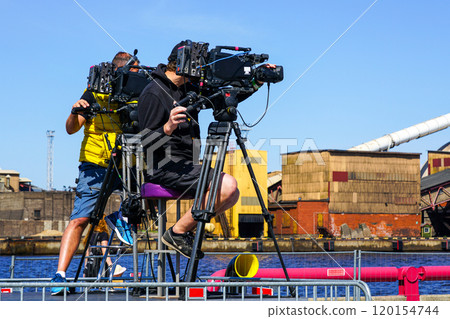 Two video operators with professional video cameras on tripods film the event Two video operators with professional video cameras on tripods film the event 120154744