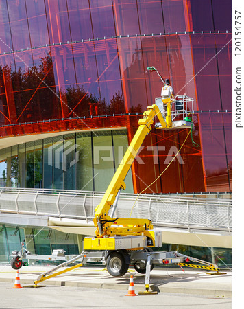 Glass facade cleaning works of a modern building using a modern telescopic boom lift with a basket 120154757