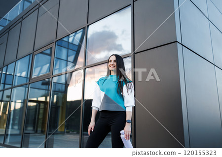 Woman holding bottle with water after morning workout. Young athletic woman standing near dark wall background after jogging Healthy lifestyle concept 120155323