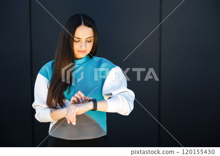Woman uses a smart watch to measure the pulse on the hands. A woman does sports on the street. Fitness and a healthy lifestyle Woman uses a smart watch to measure the pulse on the hands. A woman does sports on the street. Fitness and a healthy lifestyle 120155430