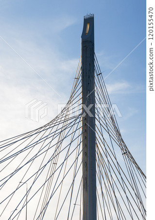 A metal cable-stayed bridge support silhouette is under cloudy sky 120155470
