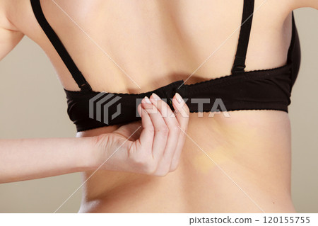 Woman dressing up her bra rear view 120155755