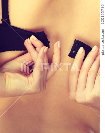 Woman dressing up her bra rear view 120155756