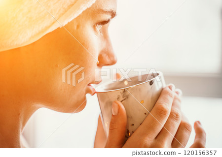 Young serene relaxed woman in spa bath towel drinking hot beverage tea coffee after taking shower bath at home. Beauty treatment, hydration concept. Young serene relaxed woman in spa bath towel drinking hot beverage tea coffee after taking shower bath at home. Beauty treatment, hydration concept. 120156357