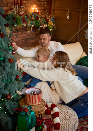Happy family decorate the Christmas tree and smiling cheerfully on Christmas Eve in a beautiful home 120156671